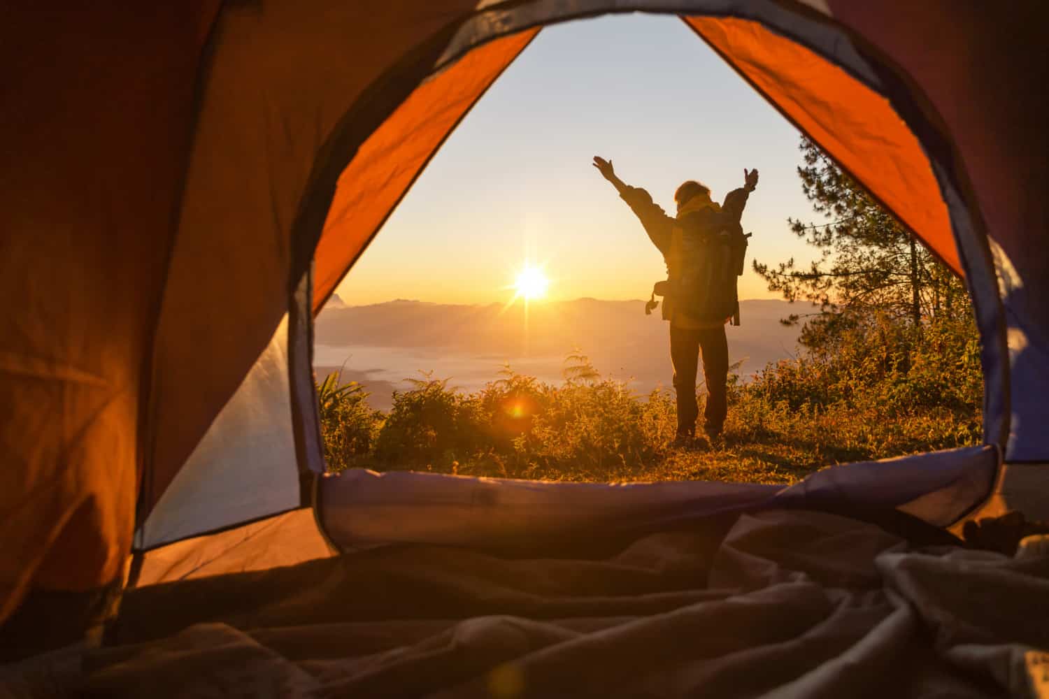 tienda de campaña con persona en el amanecer