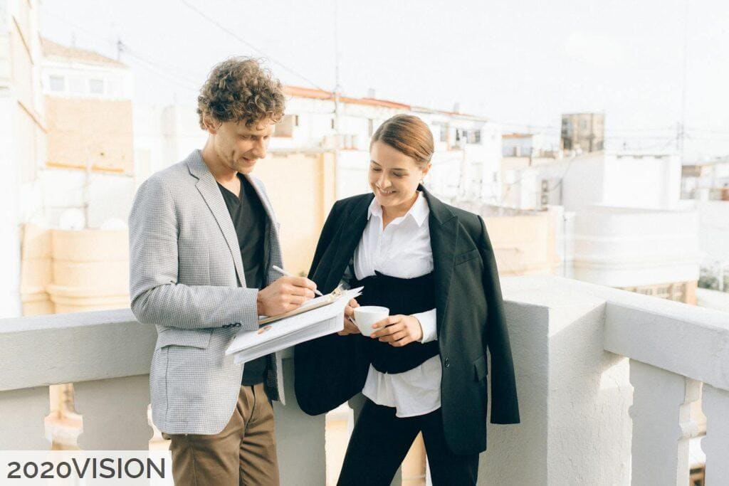 Woman in Gray Blazer Holding Book Beside Woman in Black Blazer