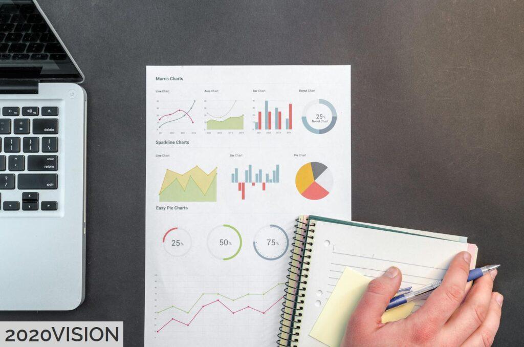 Overhead view of a business desk with charts and a laptop, ideal for data analysis concepts.