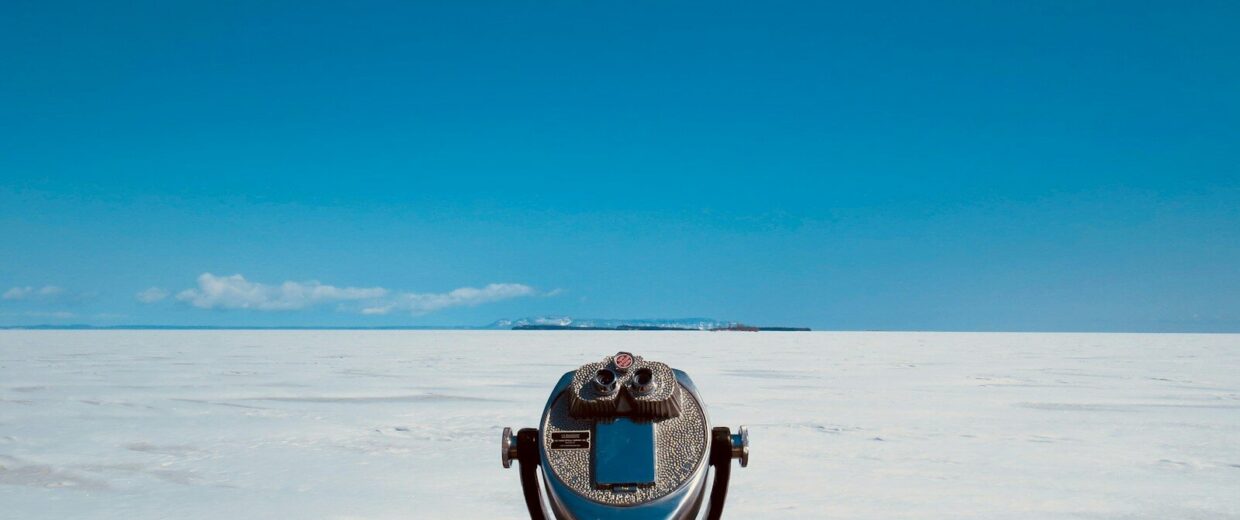 Prismáticos de mirador junto a una barandilla, con la nieve y el horizonte al fondo