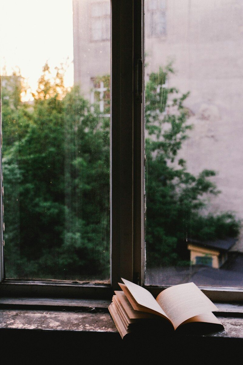 Cuaderno abierto sobre una mesa junto a una ventana con luz natural